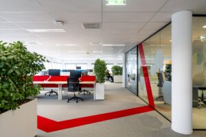 Moderne en open kantoorruimte aan de H.J.E. Wenckebachweg met bureaus, bureaustoelen, planten en glazen vergaderruimtes.